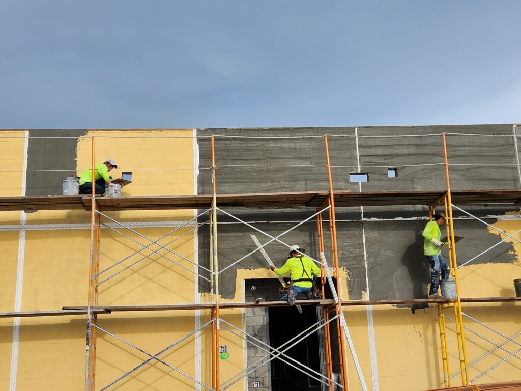 Stucco scratch coat application on a commercial building in Florida by Rayo Stucco Services, preparing the surface for a durable stucco finish.